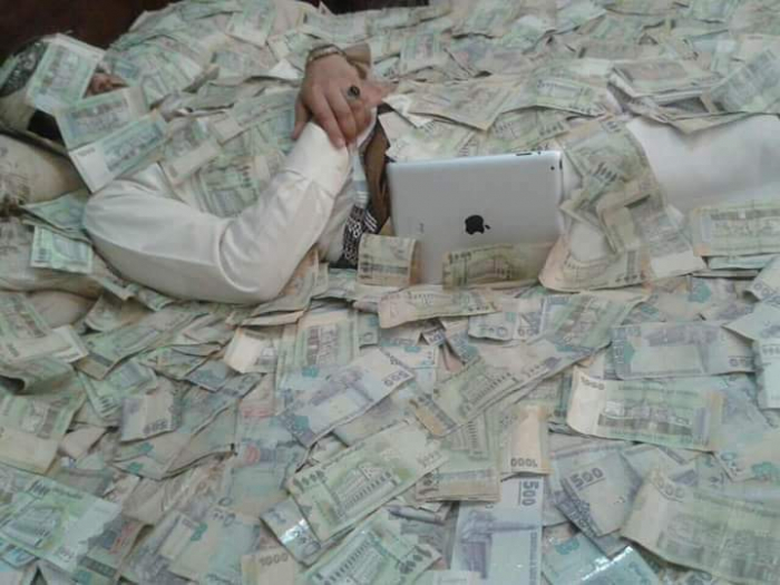 قيادي حوثي ينشر صورة استفزازية وهو نائم وسط كومة من العملة المحلية (صورة)