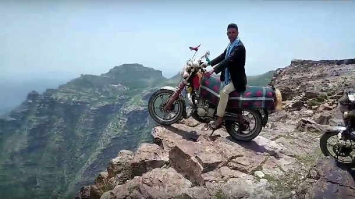 بالفيديو: شاهد مغامر يقف على مسافة صفر بدراجته النارية على حافة أحد الجبال الخطيرة في اليمن